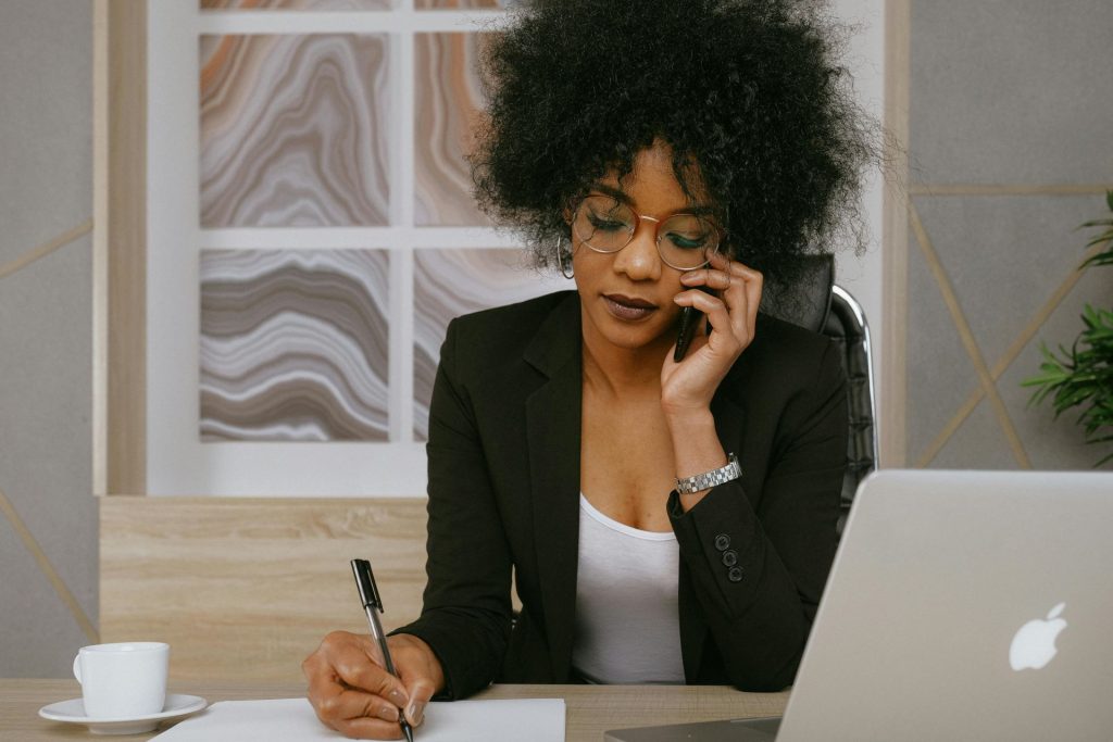 woman taking down notes while speaking on the phone 
