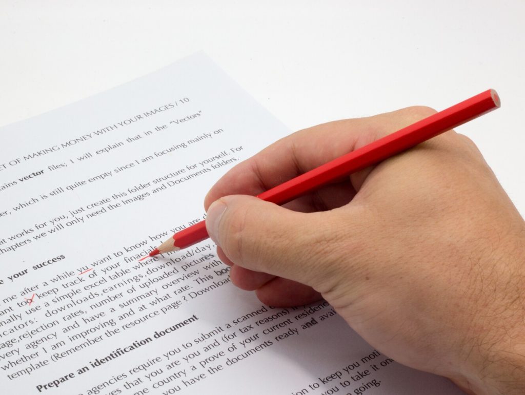 Hand doing proofreading on a faulty text with red pen