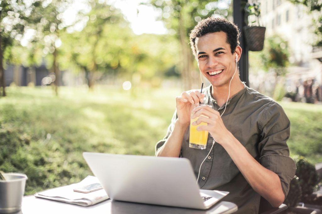 man working outside on laptop with a cooldrink