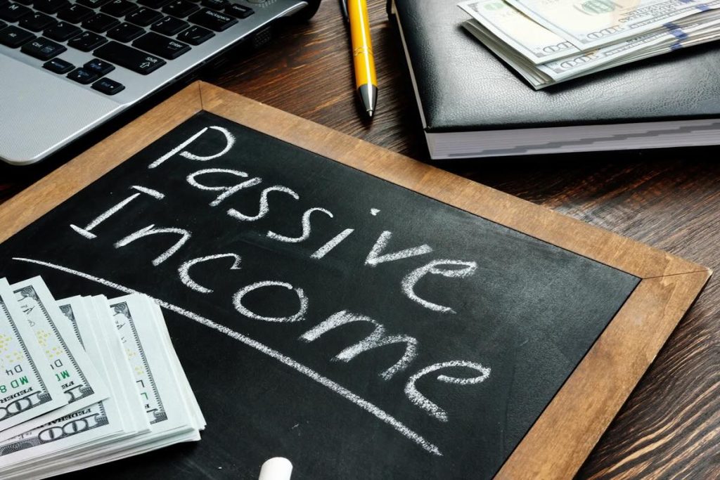 passive income depicted on a chalkboard surrounded by a laptop and cash