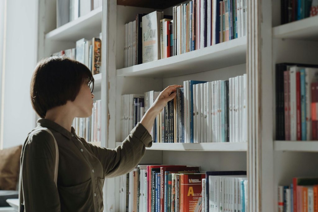 woman browsing a shelf of books 
