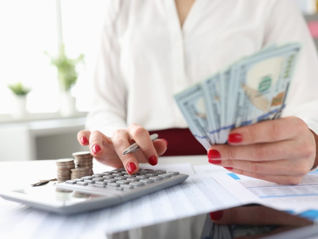 Woman holds American banknotes in her hands and works on calculator