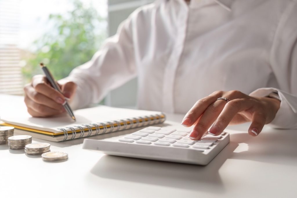 woman using calculator and writing on notepad